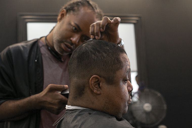 Barber trims a customers hair inside Bobby Dees.