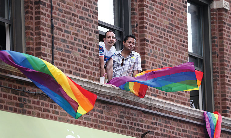 Two men watch from the window of an apartment as Jennifer Hudson performs at Chicago Pride Fest in the Lakeview neighborhood of Chicago, Ill., on Saturday, June 21, 2014. (Chris Sweda/Chicago Tribune/MCT)
