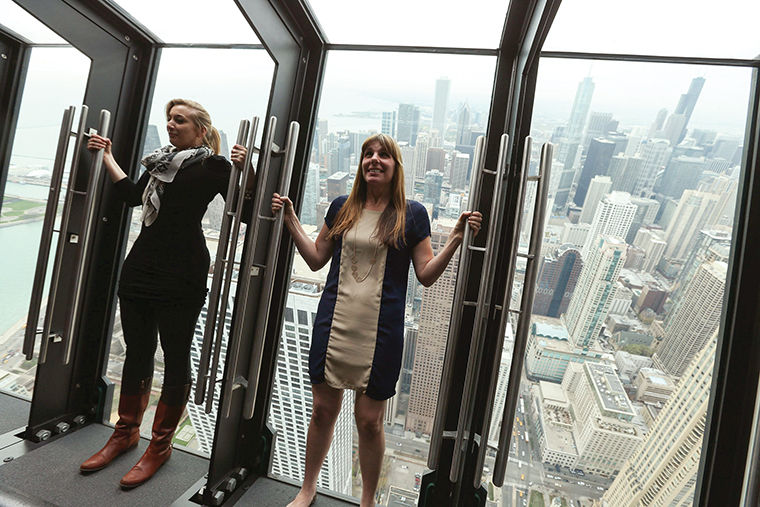 Marketing manager Leslie Cooke, left, and Laura Collins, of Isabelli Media Relations, lean back on a new attraction called Tilt which has viewers stand against one of eight glass panels that tilt out and down on an angle from the observatory in Chicago, May 7, 2014. (Phil Velasquez Chicago Tribune/MCT)