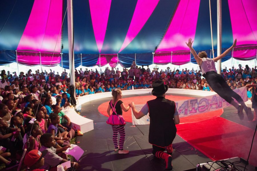 Midnight Circus performed for an audience in their little big top. Youngest member Samantha Jenkins held a banner while an acrobat leapt over it.