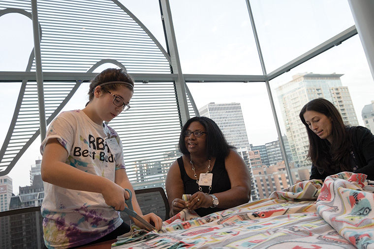 From left, Maggie Greenlees, Kishá Jones and Julie Sollinger made blankets on Oct. 21 for Robert H. Lurie Children’s Hospital patients during an event honoring co-workers who died in a 2003 fire.