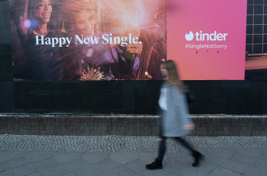 A young woman walks past a billboard advertisement for the dating app Tinder in Berlin, Germany. (Photo by Sean Gallup/Getty Images)