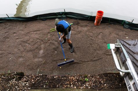 Bill Wei, consultant at Accenture, sweeps LECA, a lightweight soil made of clay pebbles, around the platform, covering the wetter areas with excess soil.