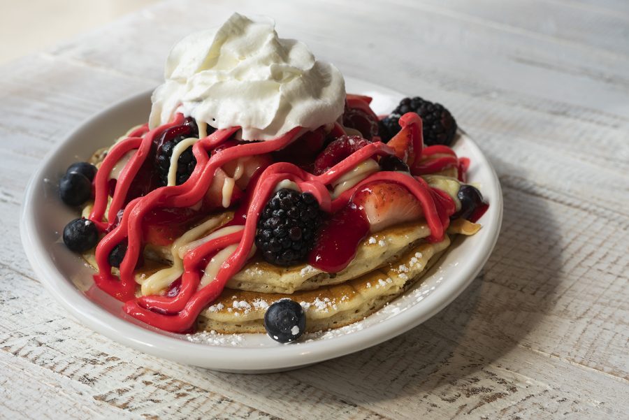 The Signature Honeyberry pancakes are topped with colorful berry mascarpone filling, fresh berries, vanilla crème angles over a spread of blackberry coulis.