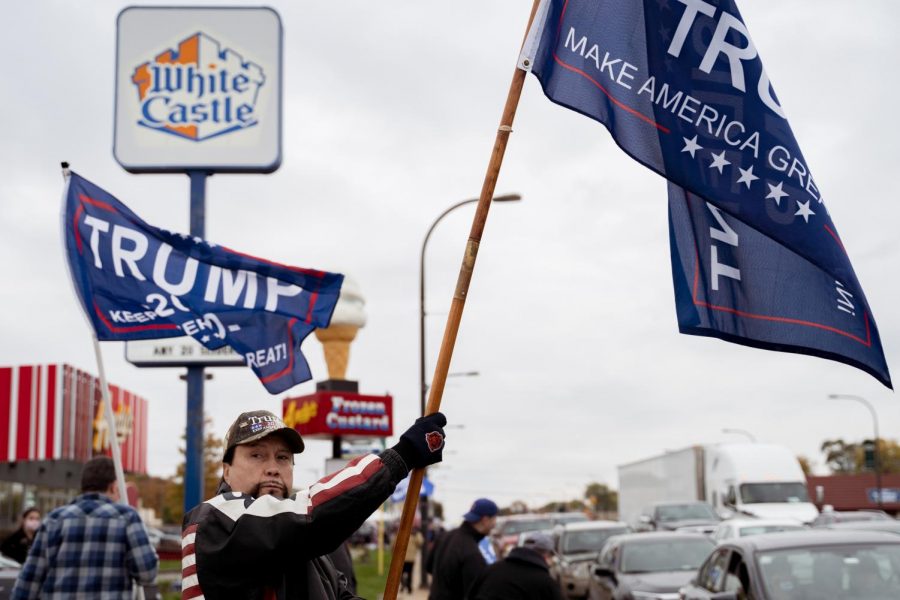 Edward Melkonian, an Orland Park resident, waves a "Make America Great Again" flag in front of a White Castle before a police car comes to control the protests.