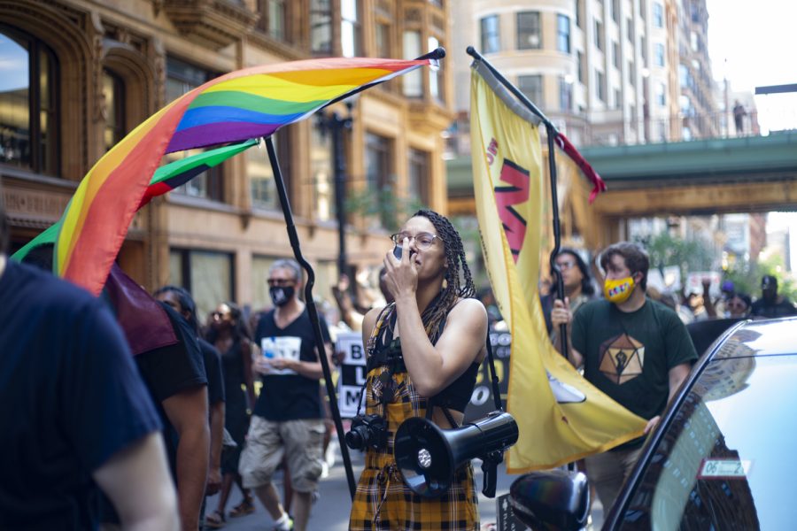 A demonstrator marches with Pride and Juneteenth flags on Dearborn Avenue during the 2021 March for Us rally.