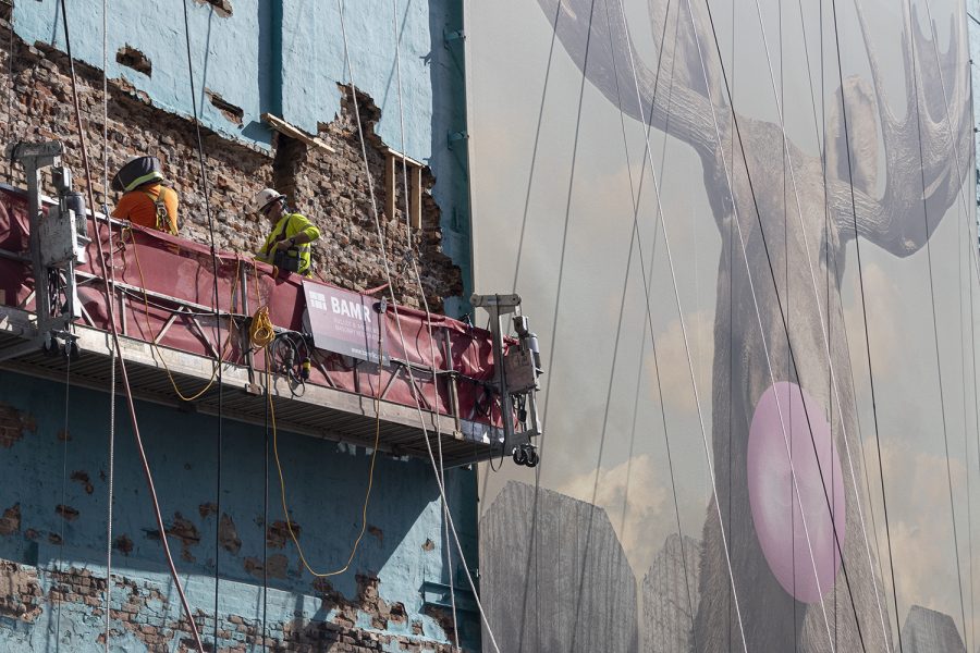 Construction crews re-point the southern brick wall of the 33 E. Ida B. Wells Drive building next to the iconic Moose Bubblegum Bubble banner on Tuesday, Aug. 24.