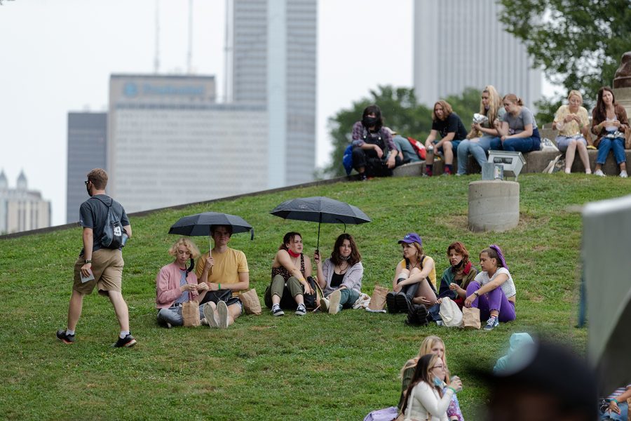 Students at Convocation sit and relax on a hill as it begins to drizzle.