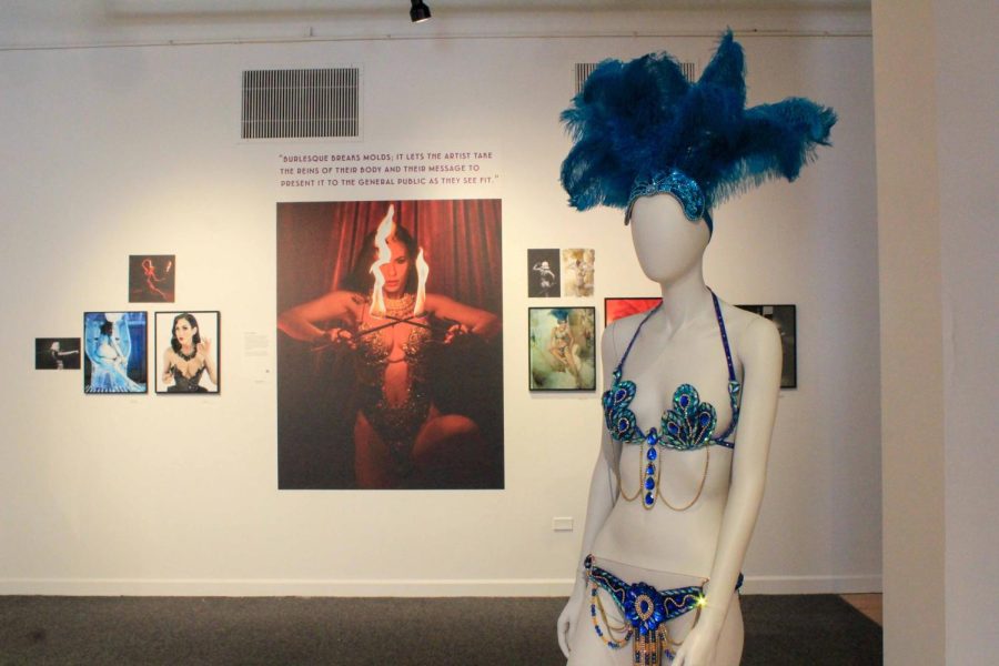 On display at the Provocative Play exhibition is the shiny and feathery blue burlesque worn by Sally Marvel, which she wore for the Harlow Pin-Up exhibition; a photo of Marvel in burlesque is also on display at the Provocative Play exhibition behind the mannequin. 