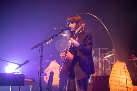 Clairo strums her guitar against a backdrop of purple lights and warm lanterns at the first of her two back-to-back shows in Chicago. 