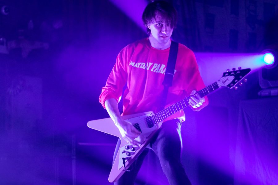 Alex Garcia, lead guitarist for Mayday Parade, is seen through a haze of purple and blue light.