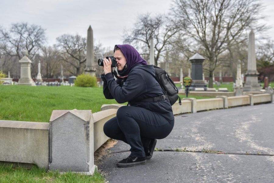 Alex Kropp, club leader and filmmaking major, takes time to appreciate the beauty of the graveyard, using their camera to take photos of the scenic landscape. 