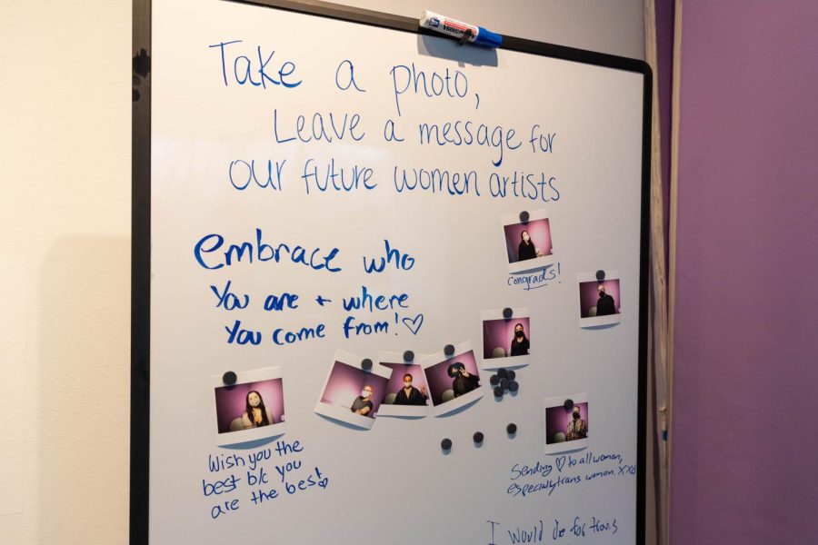 Messages of support and kind words are written across a whiteboard accompanied by a photo booth for visitors.