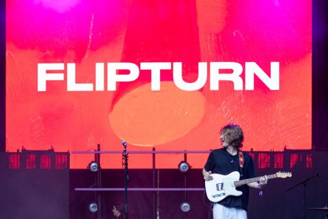 Dillon Basse, the frontman of flipturn, plays guitar against colorful visuals at Lollapalooza.