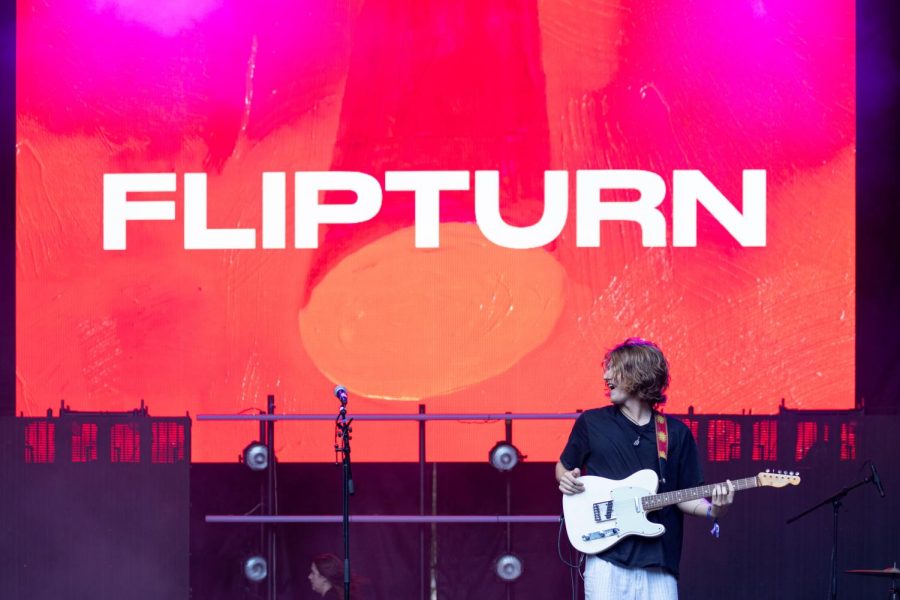 Dillon Basse, the frontman of flipturn, plays guitar against colorful visuals at Lollapalooza.