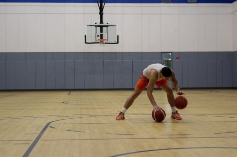 Brian Vega dribbles two basketballs at once as the sound echoes in the silent gym court as he trains. 