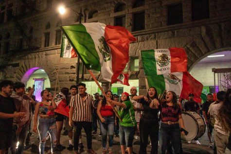 Revelers gather on Harrison Street, waving flags, playing instruments, dancing and singing together in celebration of Mexican Independence Day. 