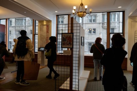 Visitors browse 24 propaganda posters made by Columbia students on March 23, 2023 at the Pritzker Military Museum & Library at 104 S Michigan Ave. Covering a range of topics, including health, beauty, politics and pollution, the works used propaganda to voice a take on modern issues.
