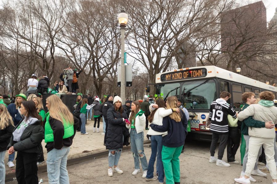 A bus is parked on Jackson Drive with a message that reads Chicago is my kind of town during the St. Patricks Day parade on Saturday, March 11. Many groups of people watch the parade along the sidewalk and street and from on top of electric boxes.
