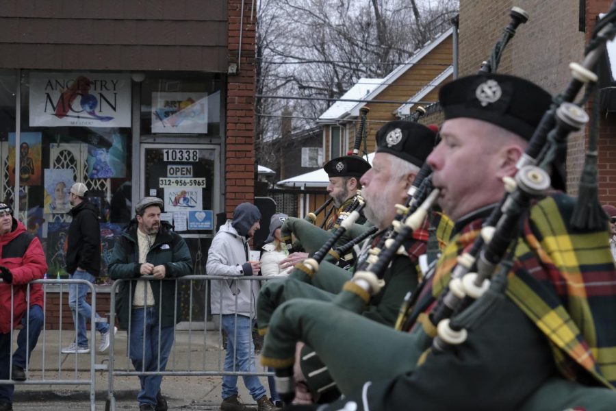 People stand along Western Avenue as members of the The Chicago Stock Yard Kilty Band play their bagpipes on Sunday, March 12. The earliest account of bagpipes in Ireland was in the year of 1206 and it is still debated where they originated from.