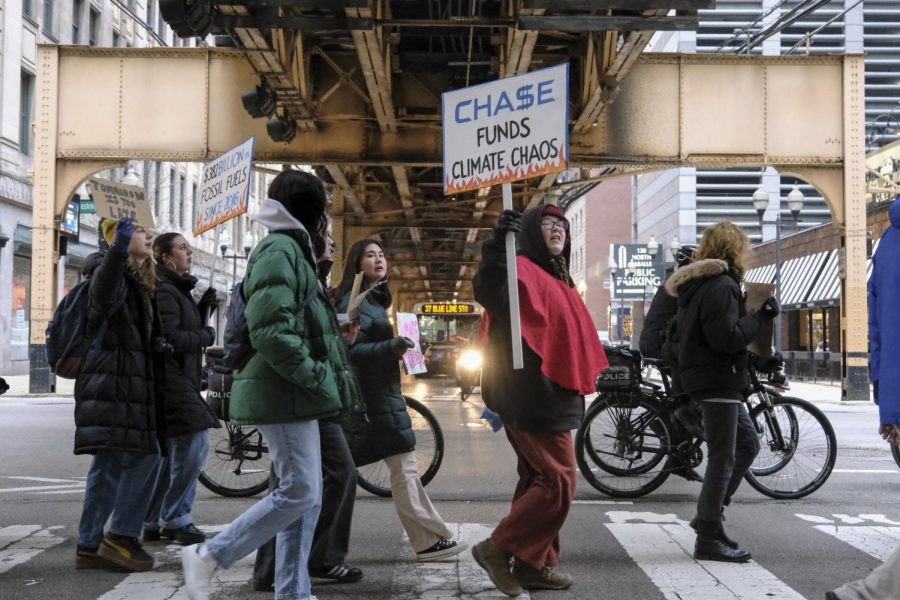 Protestors walk across the street at Washington and Wells on Friday, March 3. During the protest, protesters chanted “the planet, the people always over profit” to oppose the fossil fuel investments made by big companies such as Chase Bank.