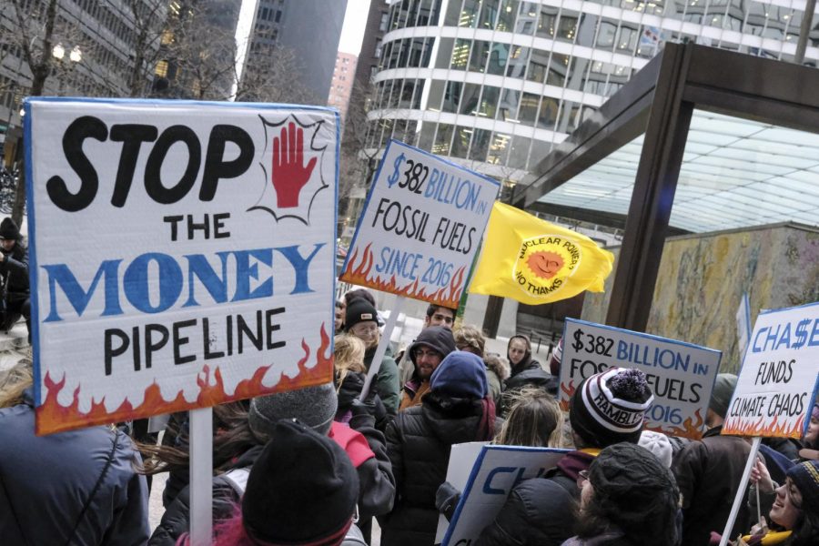 Signs carried by protestors are held during the climate strike protest in front of the Chase Tower, located at 10 S. Dearborn St., on Friday, March 3. People gathered to protest companies that invest millions of dollars in the fossil fuel industry. 
