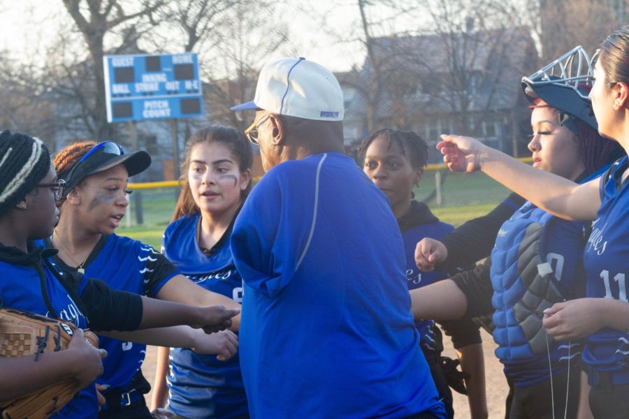 Kennard Johnson and members of the Gwendolyn Brooks varsity softball team have a huddle before a game on Monday, April 10, 2023. Johnson compares coaching sports to raising his own children and passionately supports his players. 
