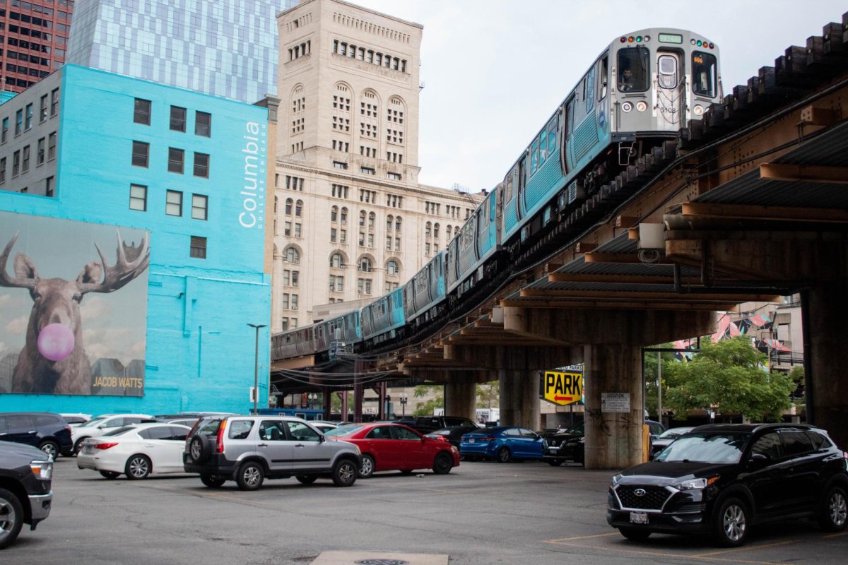 The Green Line L train heads southbound over a parking lot at E Harrison St and S Wabash Ave intersection, passing Columbias 33 E Ida B. Wells Dr. building on Friday, Aug 25, 2023.