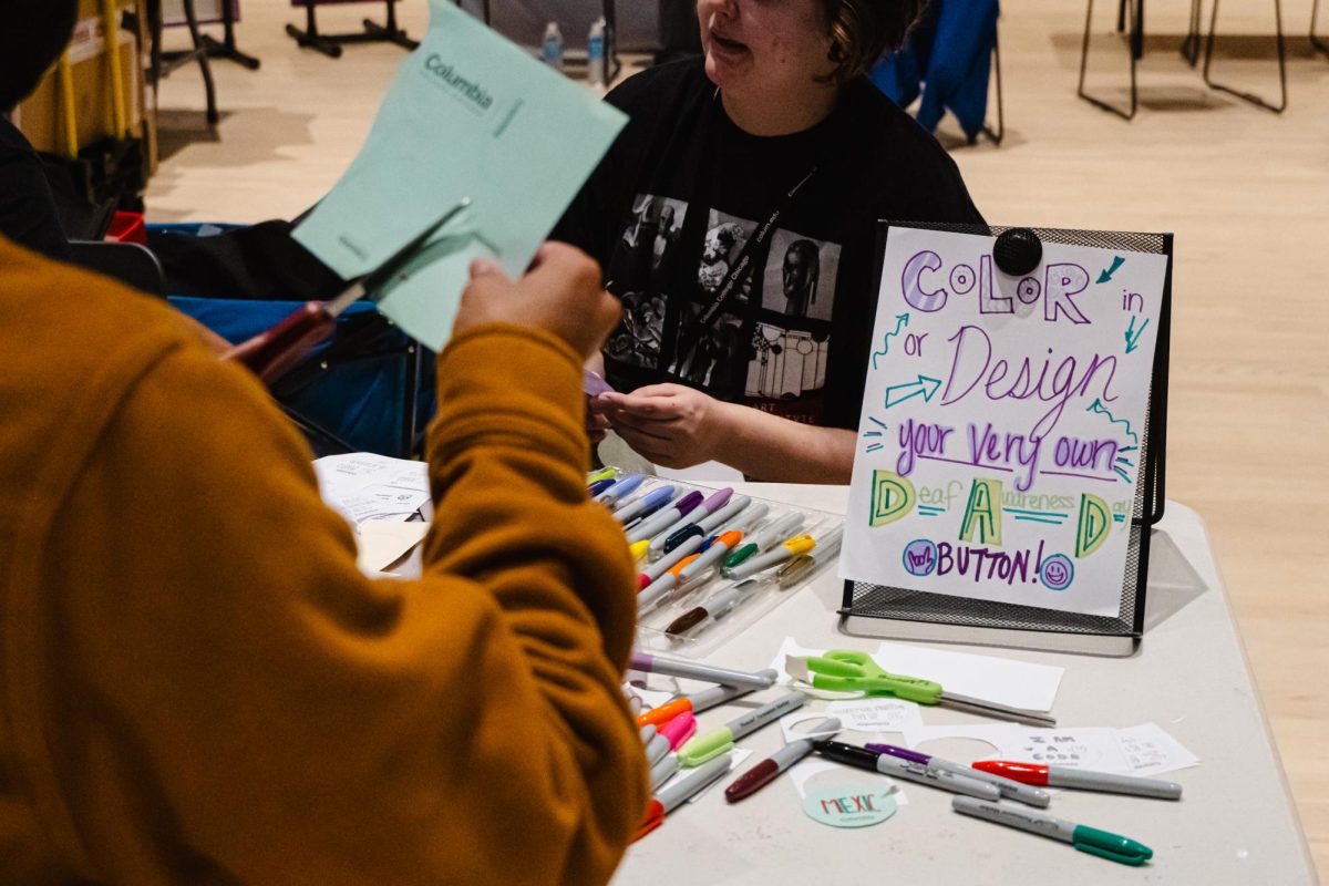 A student cuts out paper to make and customize a button on the fifth floor of the Student Center at 754 S. Wabash Ave., on Wednesday, Sept. 20, 2023. Various booths at the Deaf Awareness Day event had treats, activities, and informational organizations for students to browse.
