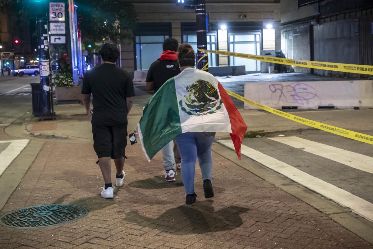 A women walks east down Ida B. Wells Drive, wearing a Mexican flag on Saturday, Sept. 16, 2023.