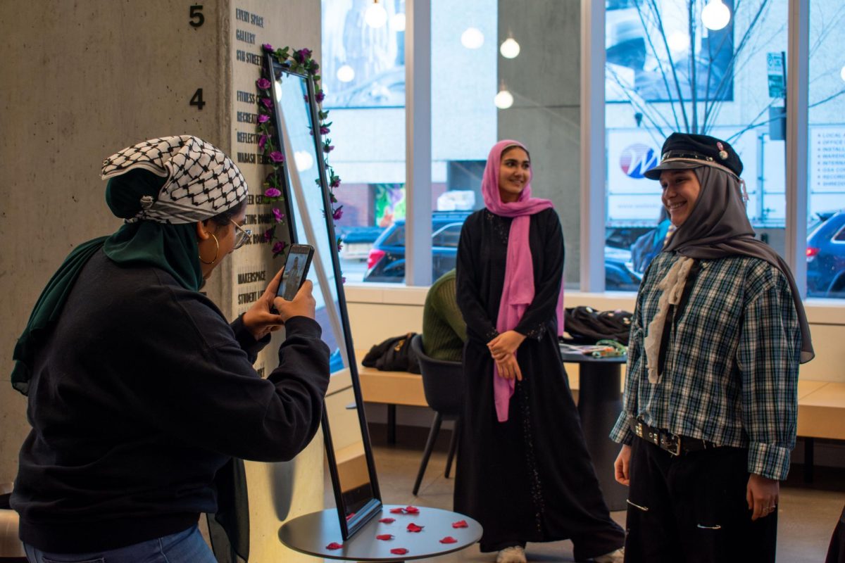 Sassy Dougherty, a junior fashion studies major gets her photograph taken by Sumana Syed, a member of the Muslim Student Association on Monday, Jan. 29, 2024. The MSA organized a booth to encourage students to try on Hijabs, look at a variety of Hijab fabrics, as well as learn the culture and meaning of wearing a hijab.