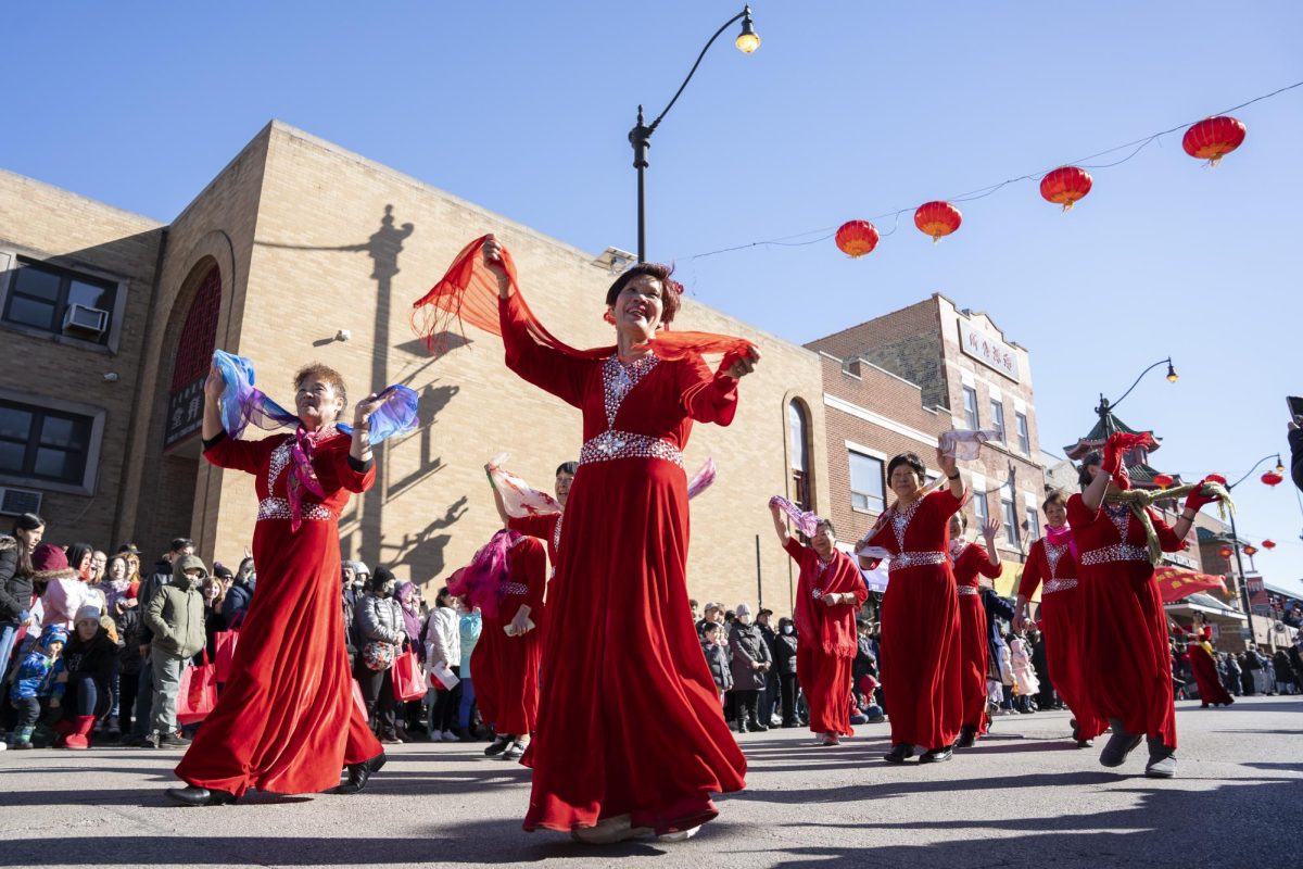 Participants of the Lunar New Year parade wave as they pass to onlookers as the parade makes its way along South Wentworth Ave on Sunday, Feb. 18, 2024.