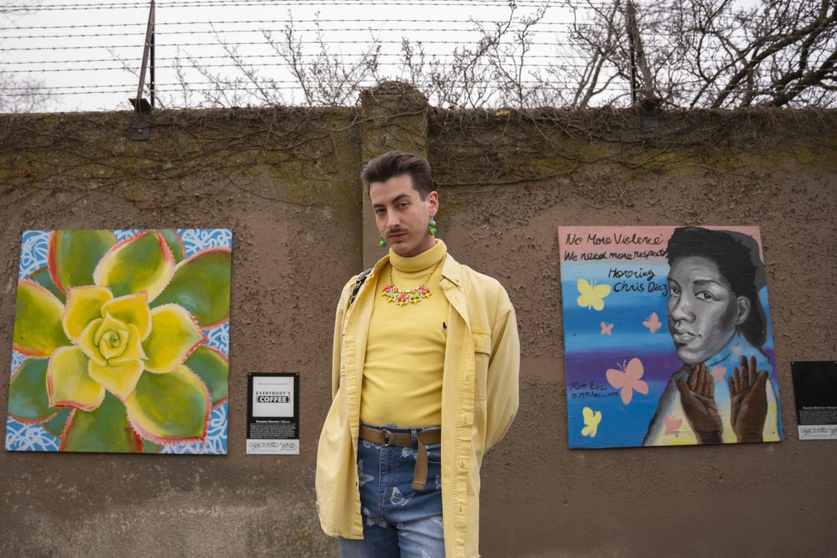 Musician and Columbia College Chicago graduate Liam Taylor, 22, poses for a photo in front of an art-decorated wall in a park near his home in Uptown, Chicago.