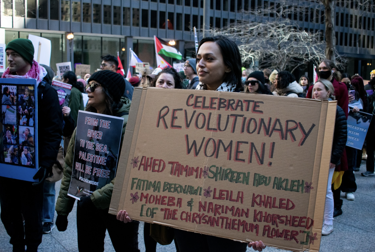 A woman holds a sign that says Celebrate Revolutionary Women, in honor of Womens History Month on Sunday, March 10, 2024. The women written on the poster are all Palestinian women who have made a change in history.
