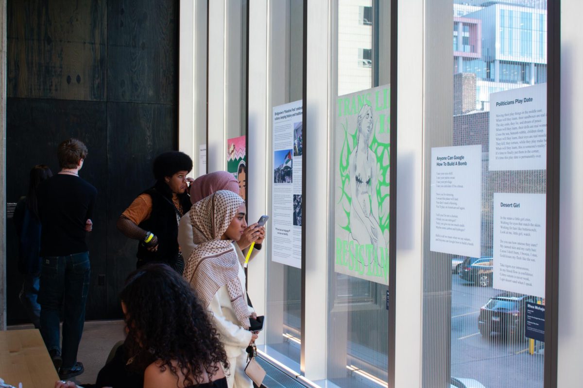 Students+look+at+artwork+dedicated+to+reflect+themes+of+oppression+on+Friday%2C+April+19%2C+2024.+Families%2C+students+and+individuals+gather+on+the+second+floor+of+the+student+center+for+the+opening+night+of+the+exhibit.