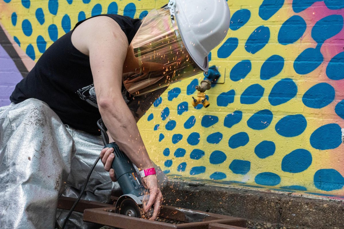 Cole Lehto, a studnet at University of Wisconsin Milwaukee, works on shaving a metal frame during Manifests Metal Pour and Yard Pong event in The Garden on Friday, May 10, 2024. Lehto, a sculpture student, came from Milwaukee to work with students for the event.