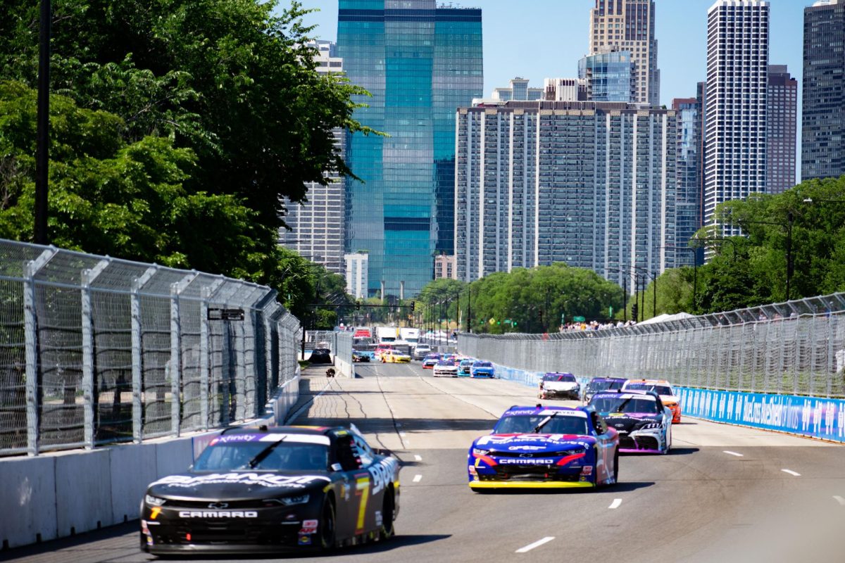NASCAR drivers zoom down Lake Shore Drive on Saturday, July 6, 2024. Fans from outside of the fence scream and point out their favorite cars. 