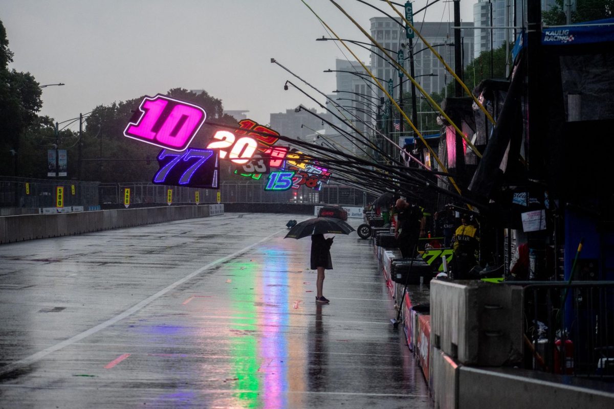 Pit crew members keep the road clear and stay dry under tents as the NASCAR Street Race announced that the race will be temporarily paused on Sunday, July 7, 2024. Each NASCAR racer has their own station with their designated race number. 