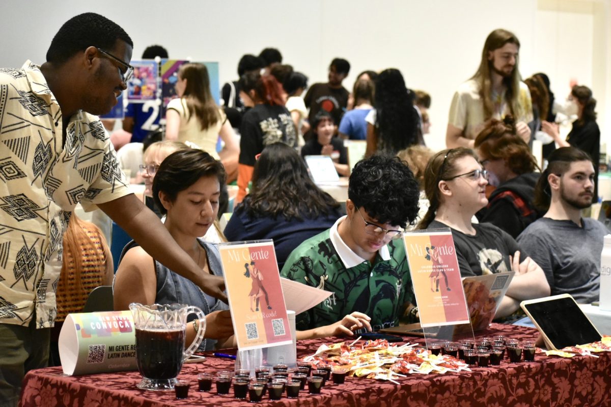 Student representatives of Mi Gente, a Latin dance club at Columbia, sit at their booth to recruit new students to join their club on Friday, Aug. 30, 2024. Mi Gente provide Latin snacks and a drink called "Agua de Jamaica" for people to try at Convocation.