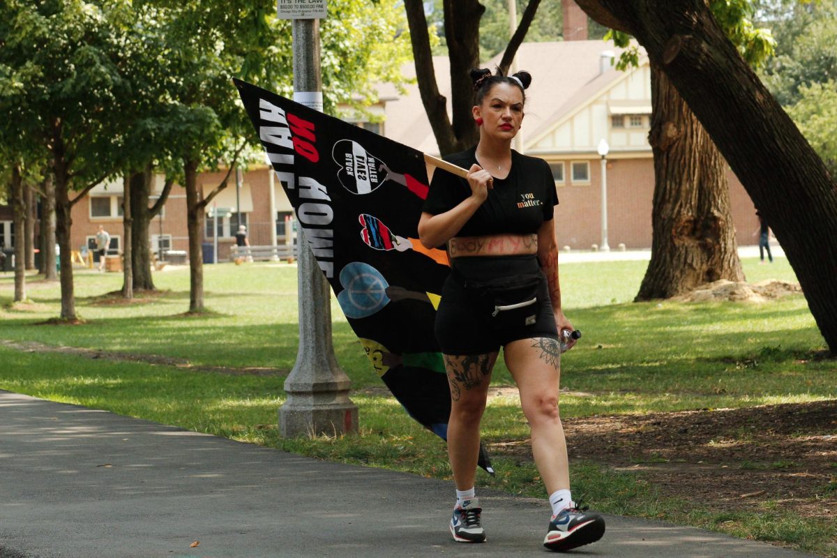 Laura Jackson walks around Union Park in Chicago with her flag that says "Hate has no home here" on Wednesday, Aug. 21, 2024.