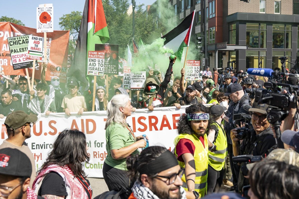 Detroit anti-war community member Mohamed Almawri holds a smoke bomb as he marches down West Maypole Avenue with the Coalition to March on the DNC on Monday, Aug. 19, 2024.