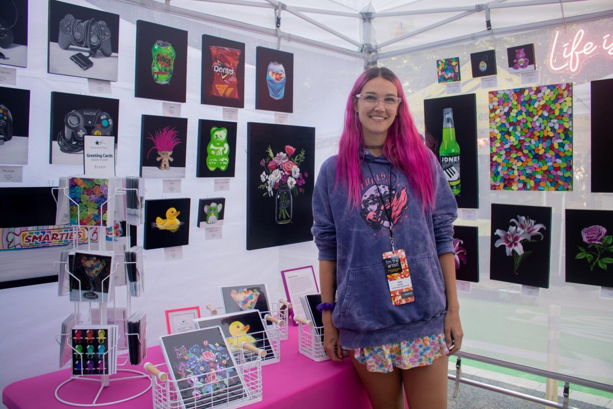 Anna Stark stands next to her brightly colored oil paintings at the Printer's Row Art Fest in South Loop on Saturday, Aug. 10, 2024.