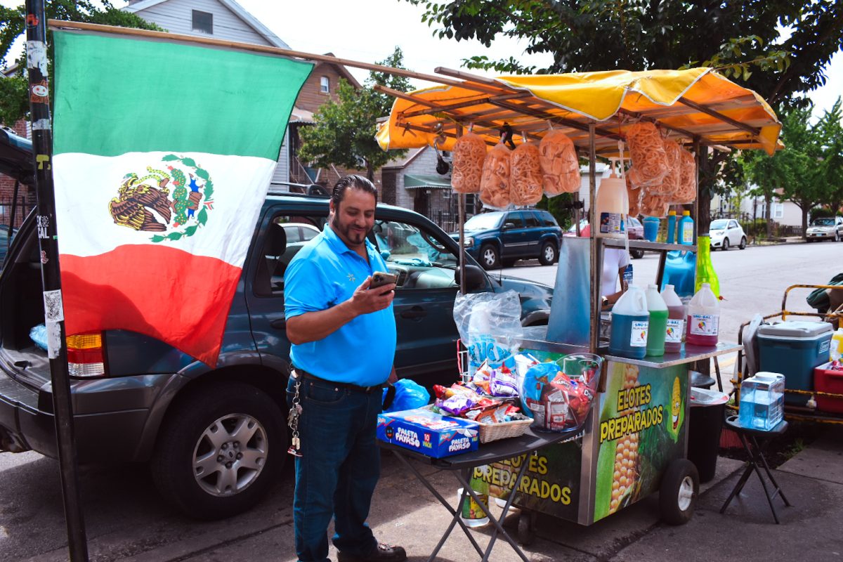 Antonio Sierra, a mexican food vendor from Michoacán, Mexico, proudly represents his culture through his food cart that displays the Mexican flag on Tuesday, Aug. 20, 2024. Sierra sells traditional Mexican snacks such as raspados, elote, and more, right in front of the National Museum of Mexican Art at 1852 W 19th St.