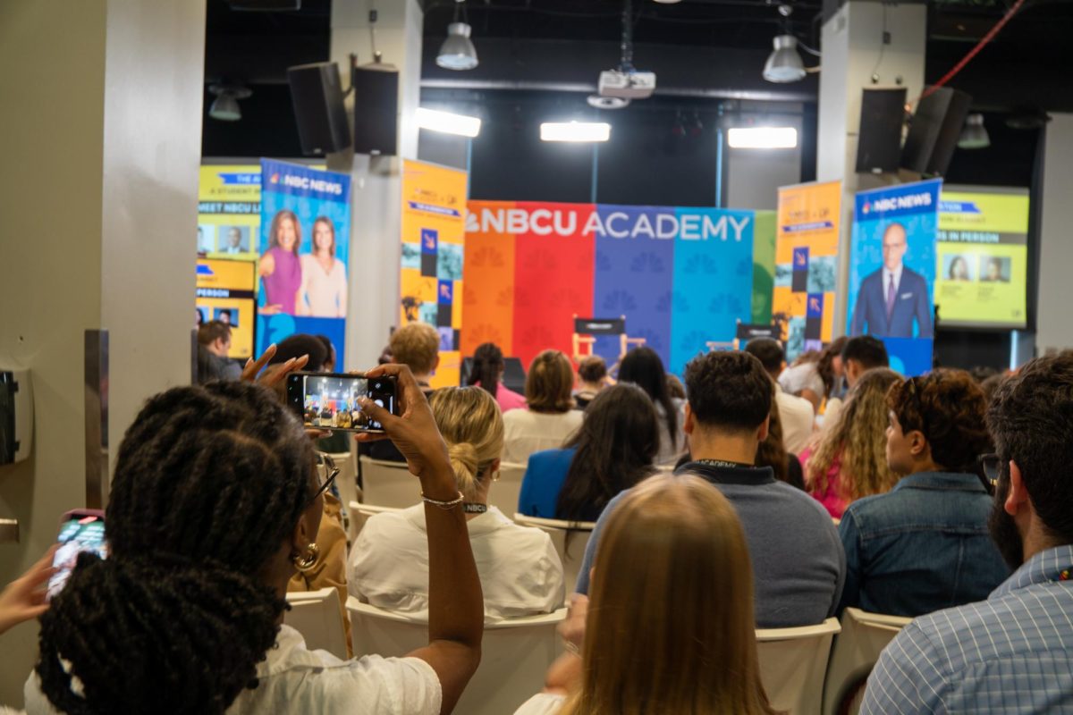 A student takes a picture of the stage before the NBCU Academy AI summit begins in the Conaway Center at 1104 S. Wabash on Wednesday, Sept. 25, 2024.