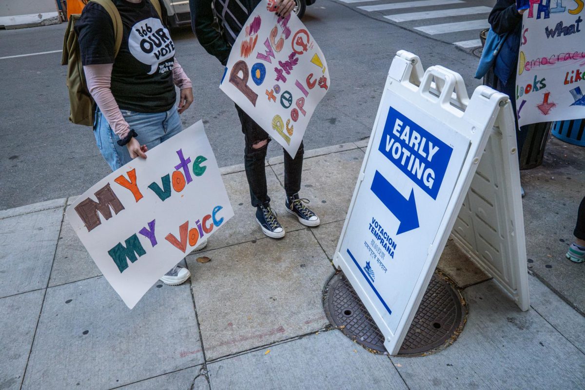 People stand outside of Chicago's early voting Supersite location with signs at 191 N. Clark St. on Thursday, Oct. 24, 2024. 