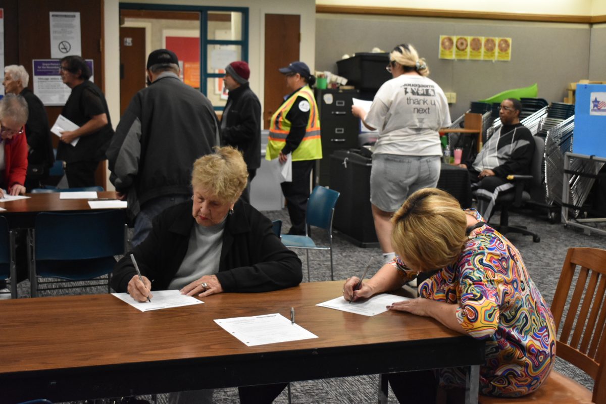 People filling out forms in preparation to begin the voting process at Chicago Public Library in the Clearing neighborhood of Chicago on Monday, Oct. 21, 2024.