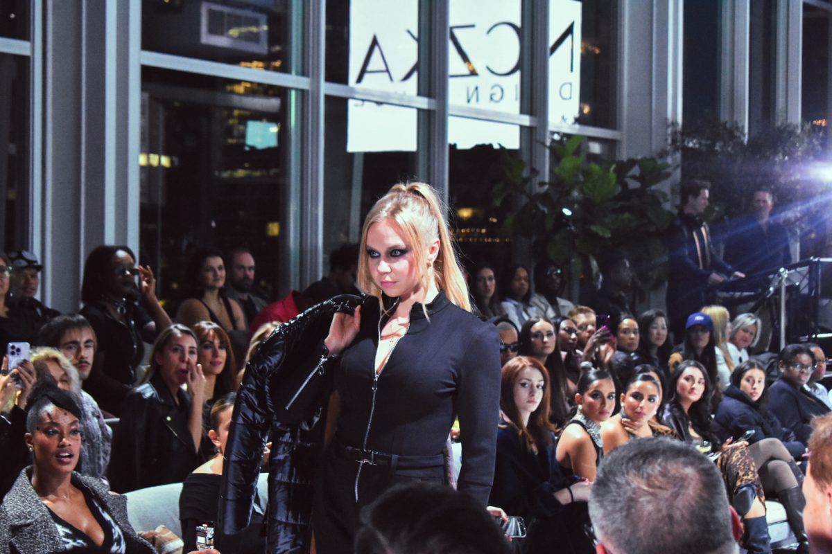 A model holds their jacket on one side as they charmingly pose at the rooftop fashion show on Thursday, Oct. 17, 2024.