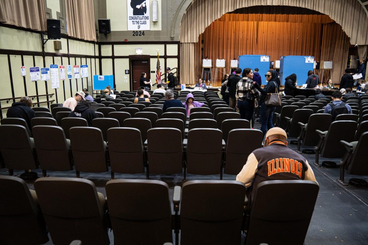 A man fills out his ballot form while sitting in theater chairs inside of Charles R Darwin Public School, the election day polling site in the Logan Square neighborhood in Chicago on Tuesday, Nov. 5, 2024.