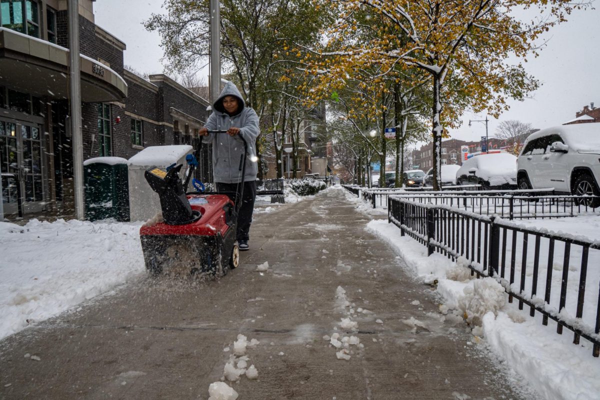 A Chicago resident clears the sidewalk in front of the Chicago Public Library in Logan Square on Thursday, Nov. 21, 2024. 