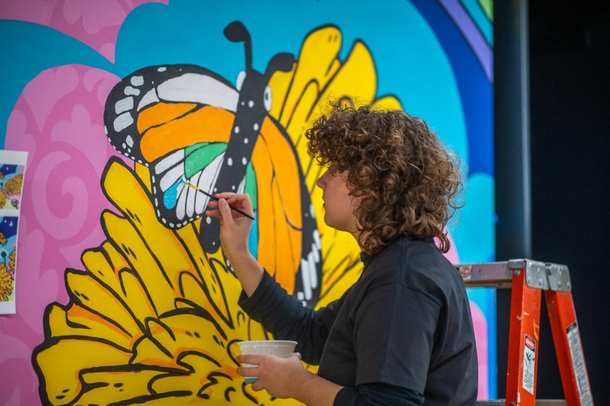 A student worker paints on an interactive wall at The Power of Persistence fundraising event at the Student Center on Dec. 5, 2024.